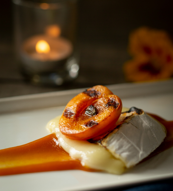 Closeup of a grilled peach on brie dessert served to meeting guests at The Kitchen at Middleground Farms