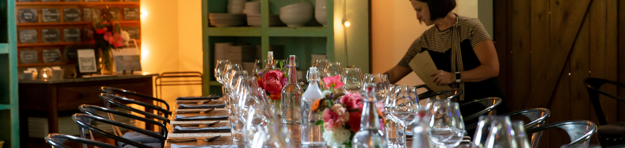 A team member prepares a dinner table for meeting guests at The Kitchen at Middleground Farms